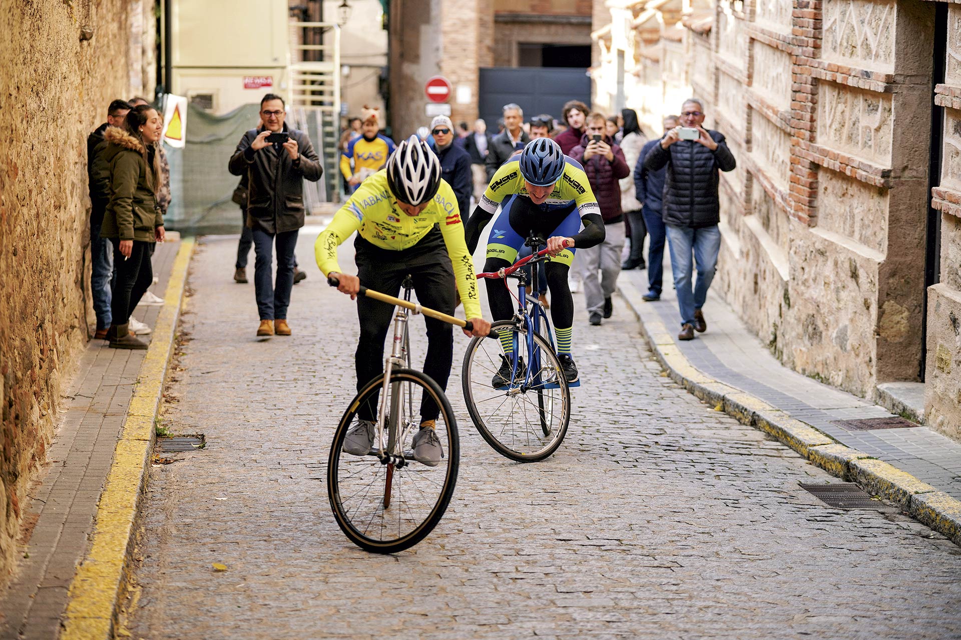 Hugo Sanz intenta remontar a Marcos García en la calle Gazzola Ceretto a pocos metros de la línea de meta, con los aficionados siguiendo a los corredores./ MIGUEL ÁNGEL FERNÁNDEZ