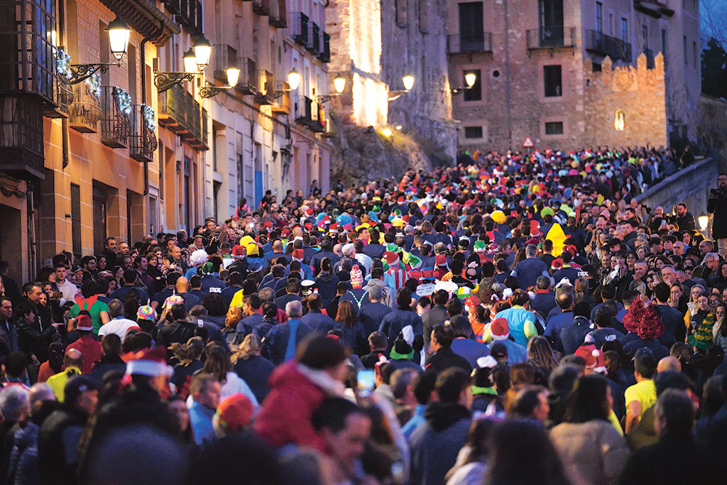Espectacular imagen de los atletas intentando ascender por la calle San Juan, repleta de espectadores, en una mezcla que solo se produce en la Carrera Fin de Año./ MIGUEL ÁNGEL FERNÁNDEZ