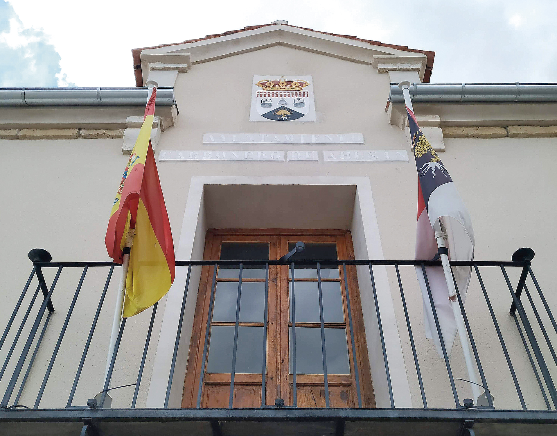 Escudo y balcón con las banderas oficiales en el Ayuntamiento de Carbonero de Ahusín. / E. A.