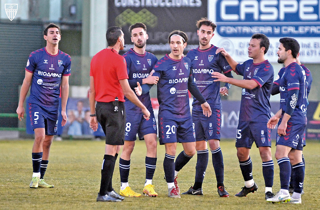 El árbitro del Segoviana-Leganés, dialoga con los jugadores azulgranas en la despedida de Adrián./ JUAN MARTÍN-G. SEGOVIANA
