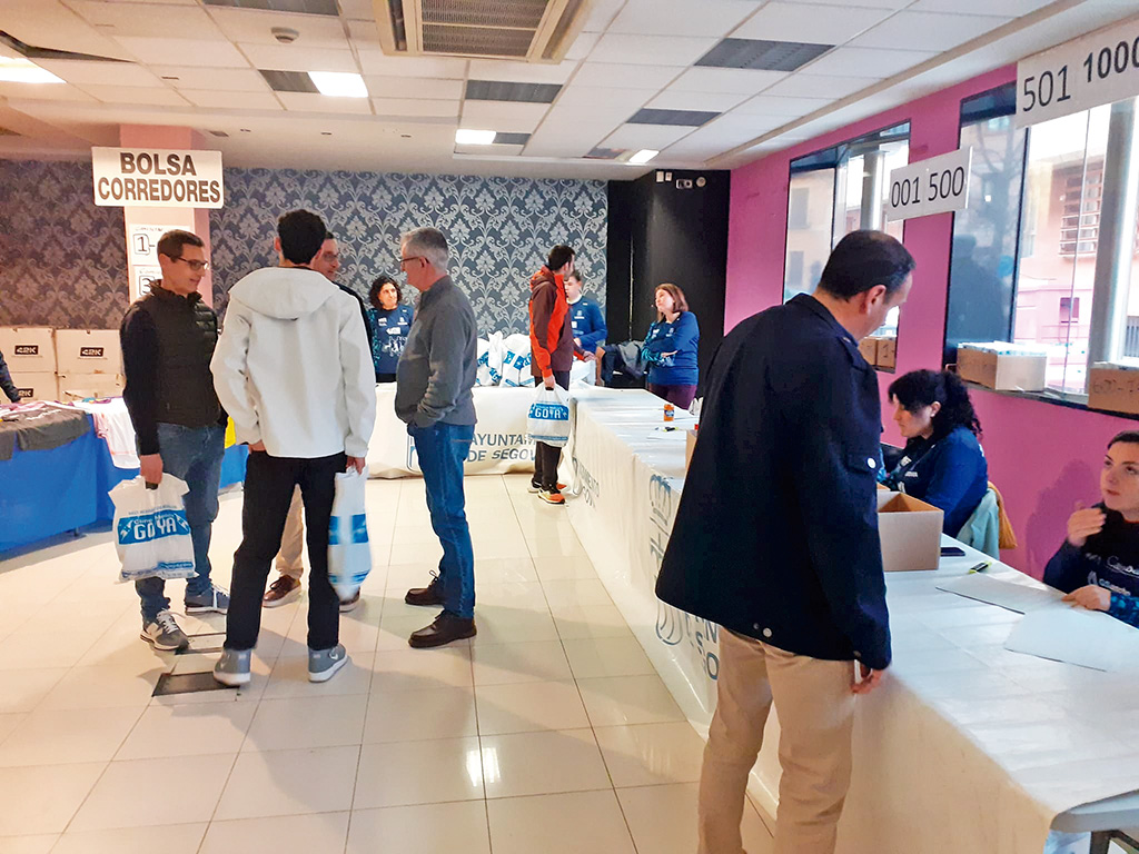 Los voluntarios, informando a los corredores y entregando los dorsales en el local habilitado en la plaza de Somorrostro./ J.M.