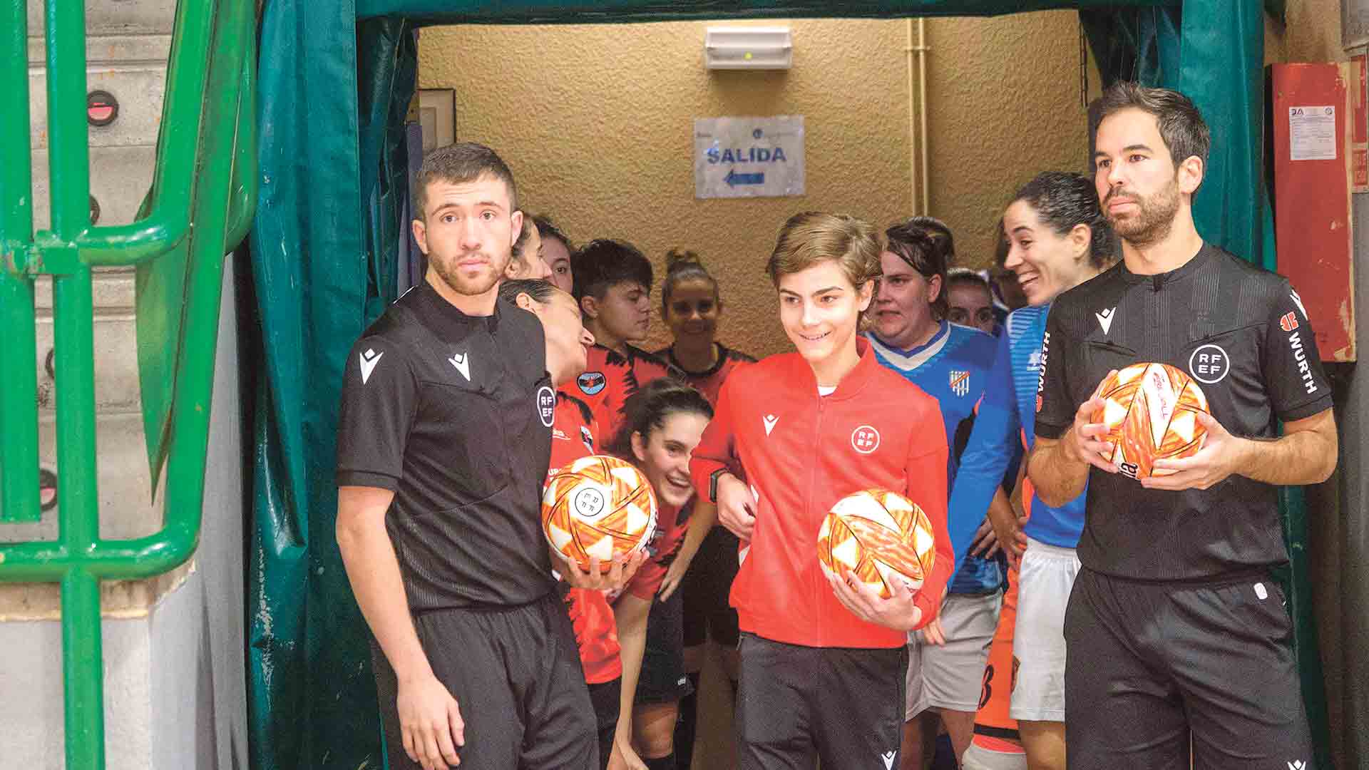 Dos árbitros, esperando el momento para entrar a la cancha durante los prolegómenos de un derbi femenino de fútbol sala./ KAMARERO