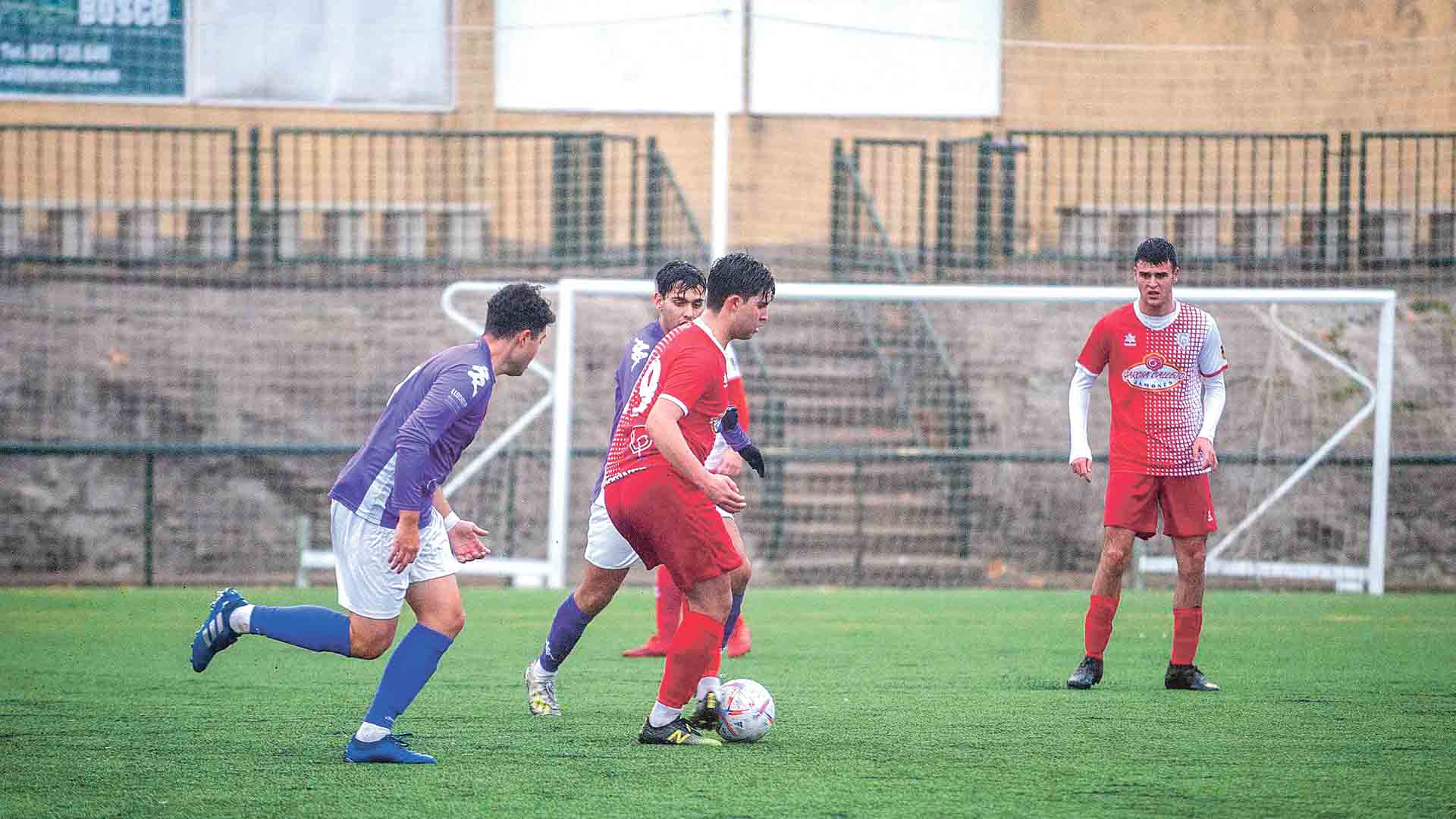 El jugador del CD Carbonero intenta pasarle el balón a un compañero./ KAMARERO