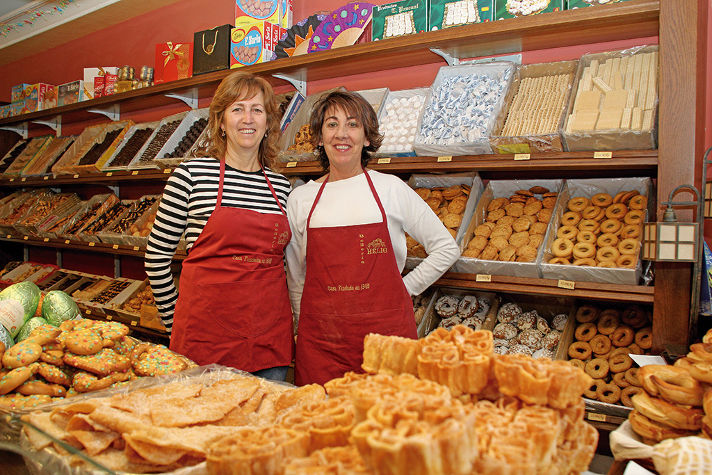 Mari Carmen y María Henar en su bollería, rodeadas de sus productos. / C.N.
