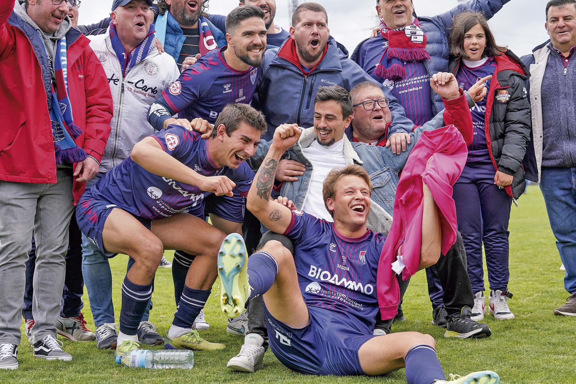 Varios jugadores de la Segoviana celebran con los aficionados en el campo su clasificación./ M.A. FERNÁNDEZ