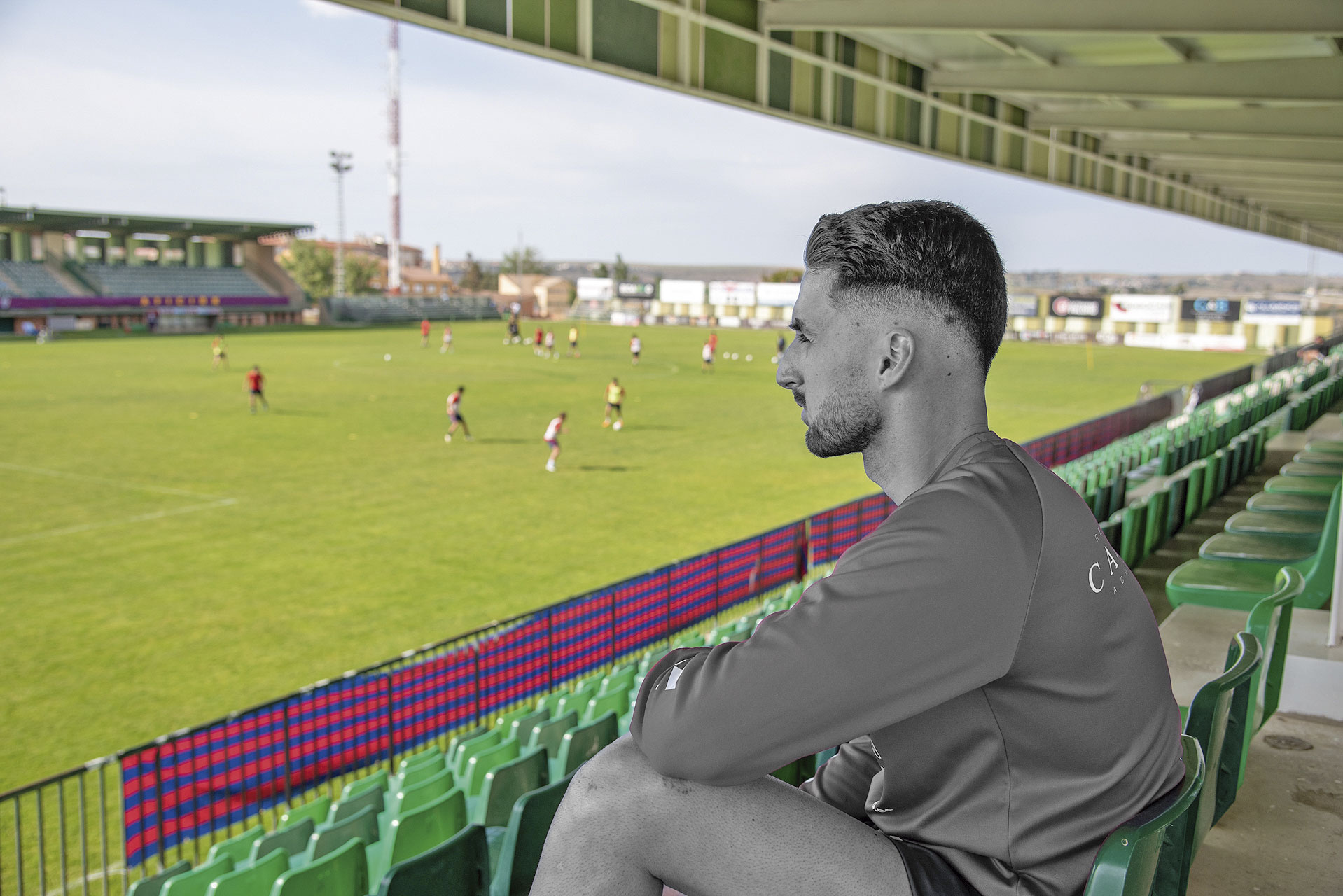 Hugo Díaz, retocado en la fotografía en blanco y negro, observa el entrenamiento de sus compañeros de la Segoviana./ LUIS HORCAJADA