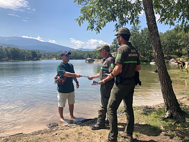 Agentes medioambientales entregan folletos de advertencia a un bañista.