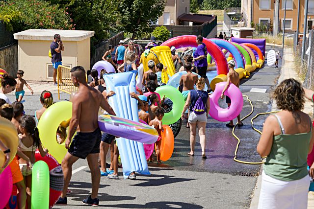 Numerosos asistentes hacen fila para el tobogán acuático. / Miguel Ángel Fernández