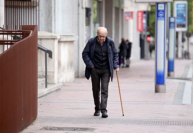 Una persona mayor camina por la calle.