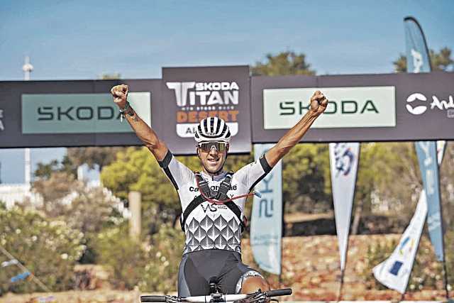 Fran Herrero levanta los brazos tras acabar la etapa en la primera posición./ TITAN DESERT