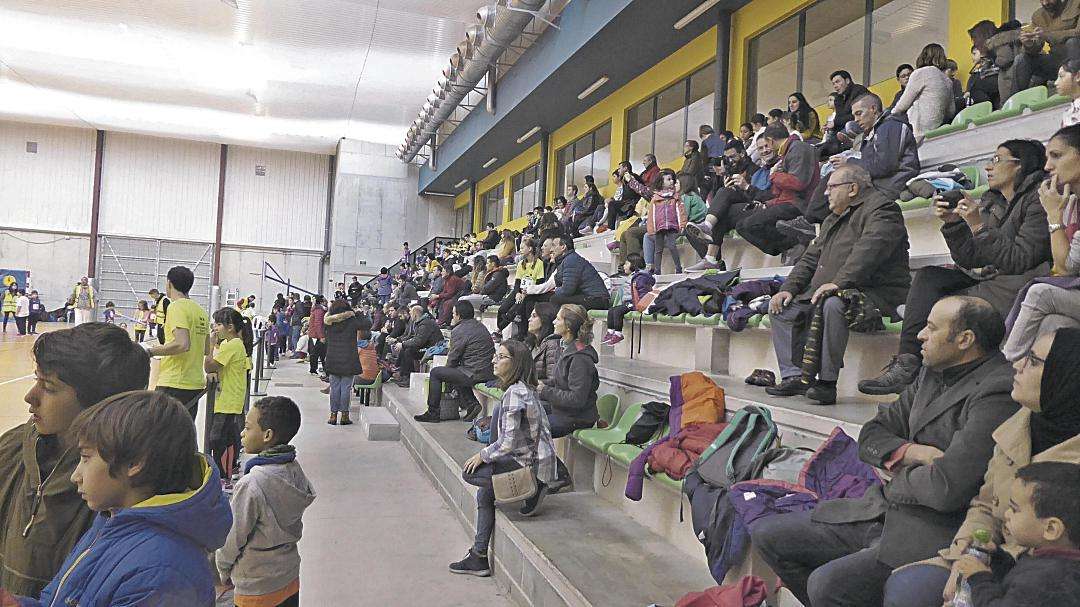 Padres y madres disfrutando de las actividades realizadas por sus hijos en el polideportivo.