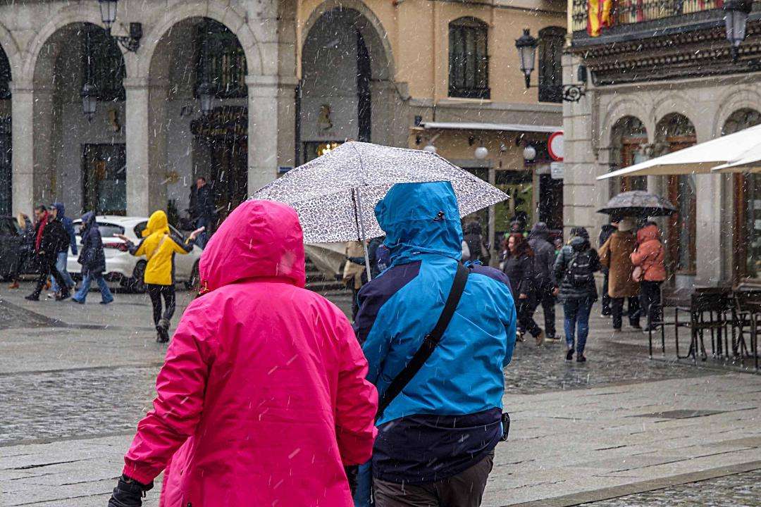 Turistas pasean bajo la nieve en una foto de archivo