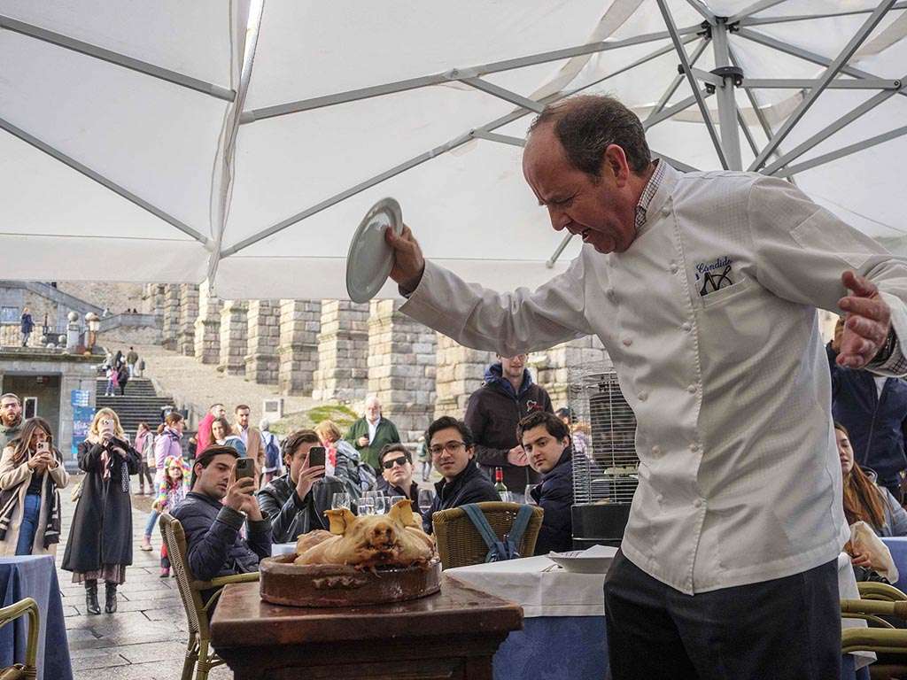 Cándido López, ofreciendo a los comensales un cochinillo, en la terraza del establecimiento. / KAMARERO