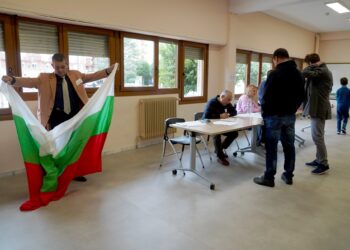 Un voluntario extiende una bandera de Bulgaria durante la votación en Valladolid./ ICAL