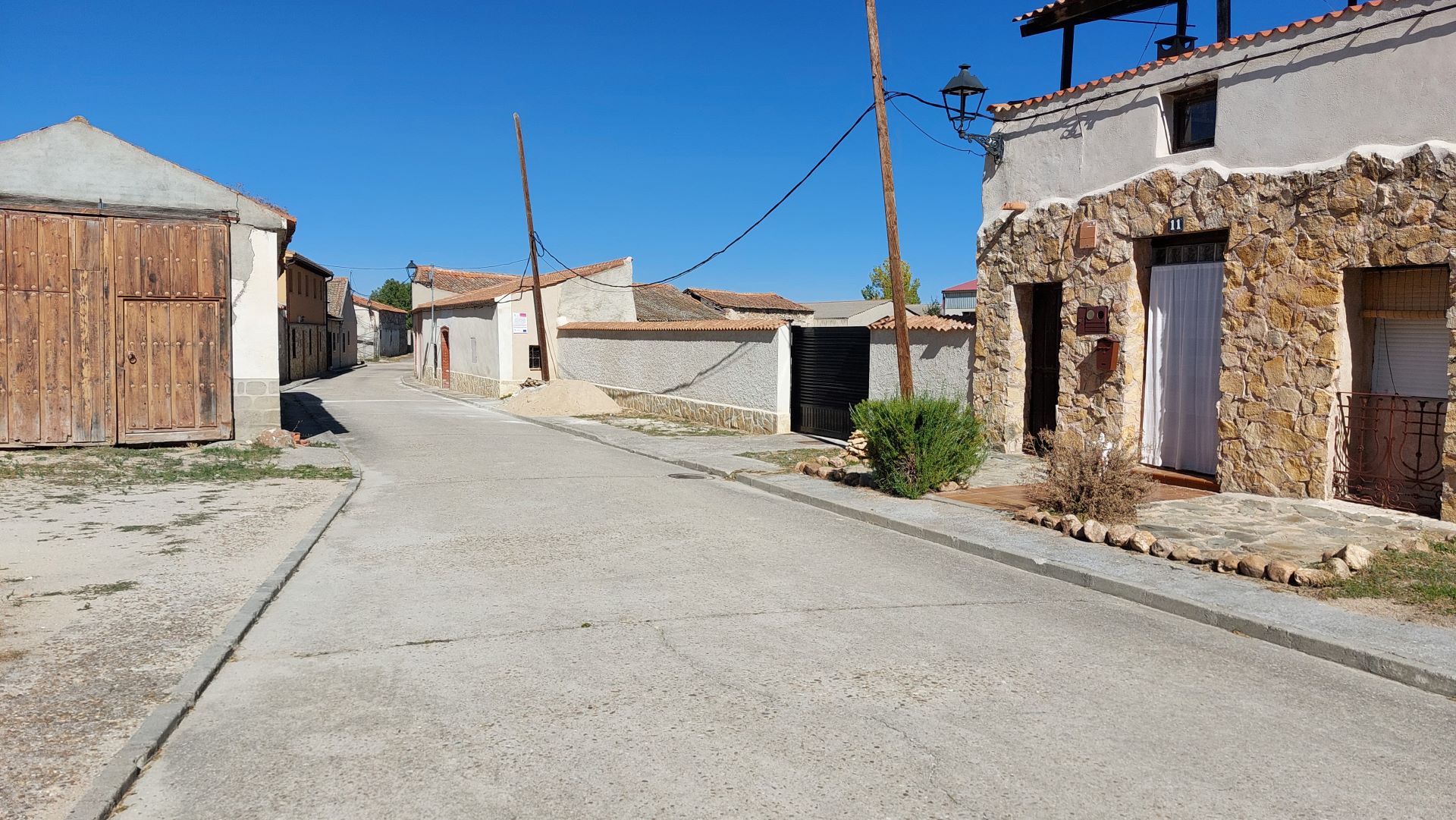 Las joyas de Paradinas (I): la villa romana y su desventurada trayectoria vital 9 Vista actual de la calle Real de Paradinas. En primer plano, bajo el asfaltado actual, se ubicaba el Ámbito I excavado en 1968, mientras que al fondo se aprecia una tapia que protege el solar en el que se excavó ese mismo año el Ámbito II y donde se han retomado las excavaciones en 2021 y 2024.