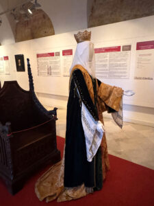 Maniquí representando a la reina Isabel, con el trono detrás.