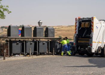 Dos trabajadores de la empresa concesionaria del servicio de recogida de residuos, dejando uno de los contenedores en su lugar  tras vaciar su contenido./ E.A.