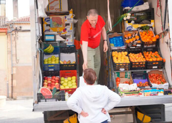 Un encargado de una frutería, atendiendo a un cliente.