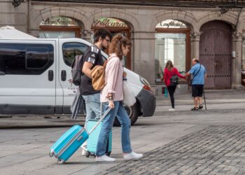 Dos jóvenes con maletas cruzan la Plaza Mayor. /NEREA LLORENTE