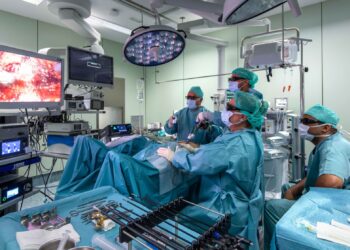 Médicos y enfermeras, observando una pantalla durante una operación quirúrgica./ BETTER CARE