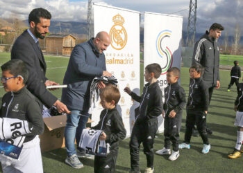 Jesús Garrido, en el centro, entrega material deportivo a los alumnos de la escuela de la Fundación Real Madrid junto a Arbeloa. E. A.