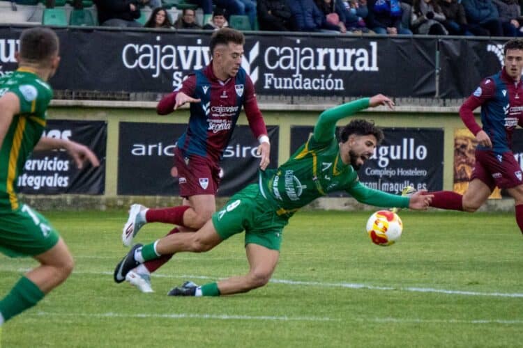El juagdor del Atlético Astorga cae ante la presencia de Diego Campo durante el encuentro jugado en La Albuera./ HÉCTOR CRIADO