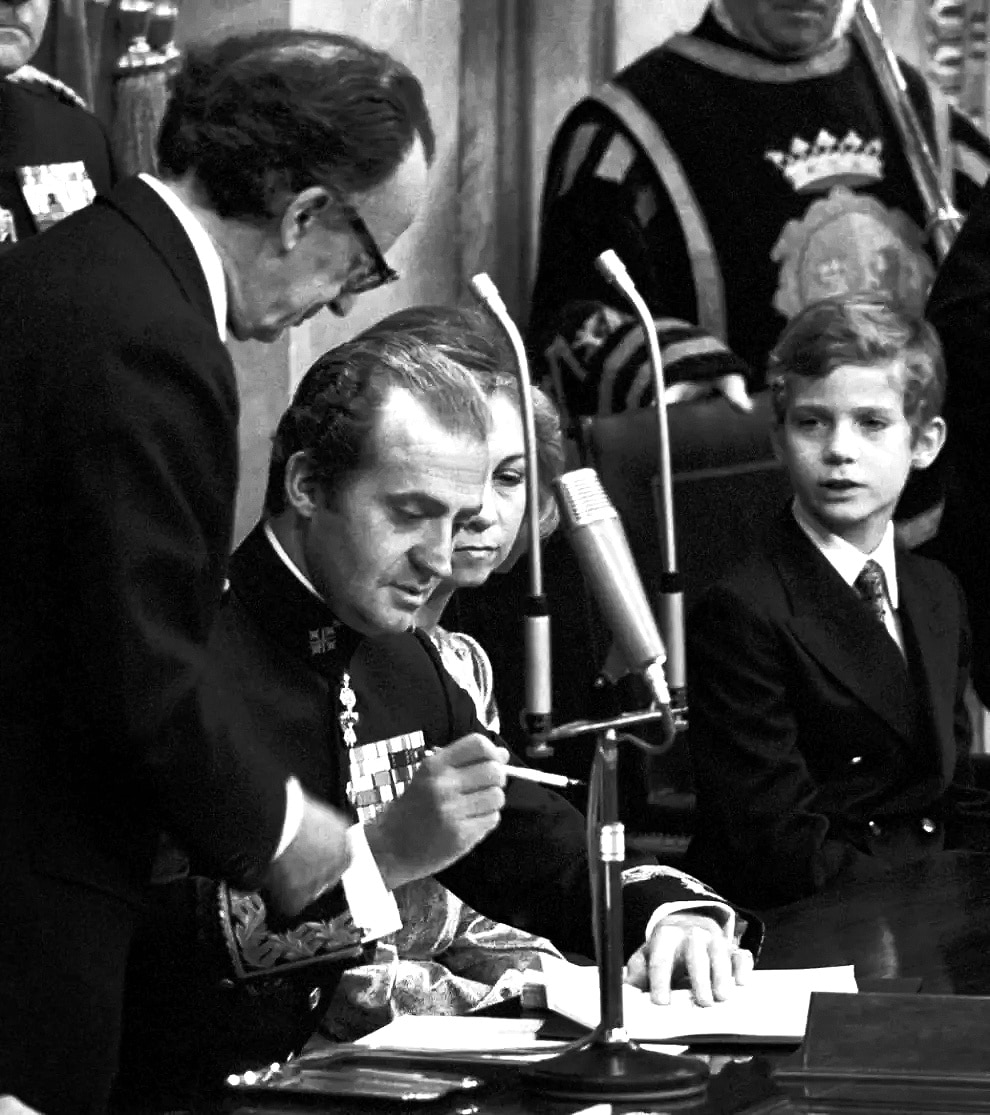 La última curva 2 Juan Carlos I sancionando la Constitución en presencia de la reina Sofía y el príncipe Felipe.