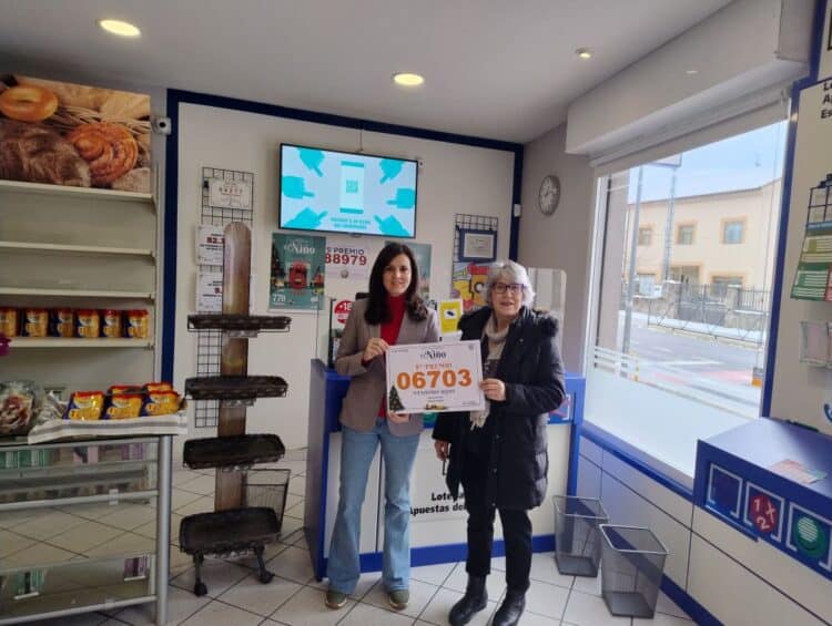 Paloma, con su hija Irene muestran el número vendido en su establecimiento, el primer premio.  / M. A. R.