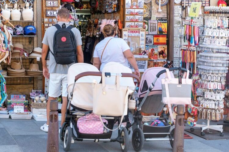 Una pareja con varios carritos de bebé frente a una tienda.