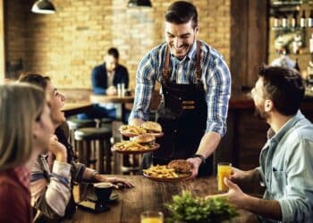 Un camarero sirviendo la comida a los comensales. / Magnific